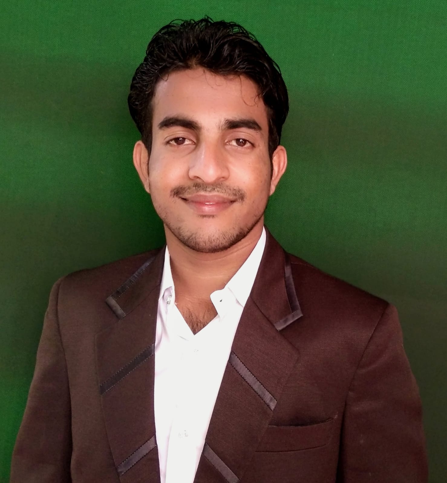 Man in blue suit standing in front of green chalkboard with arms crossed and smiling confidently
